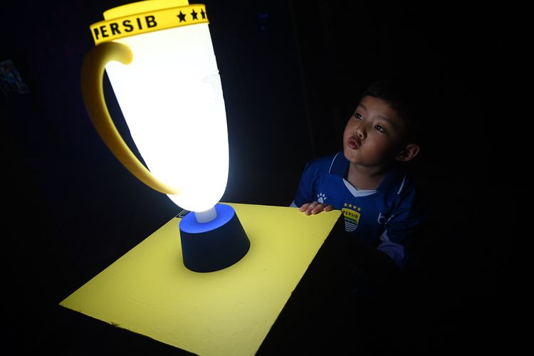Ekspresi seorang anak berbaju Persib Bandung terkesima melihat simbol piala yang berhasil diraih Maung Bandung dalam tiga musim terakhir, dipajang di pameran Cultura Persib di Grey Art Gallery, Jl Braga Bandung, mulai Senin (8/6/2026).