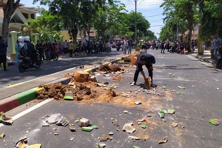 Seorang mahasiswa yang ikut aksi unjuk rasa, membersihkan sisa-sisa pot bunga yang berserakan di jalan setelah terjadi kericuhan dalam aksi unjuk rasa di depan kantor DPRD Pamekasan, Jumat (27/9/2019)