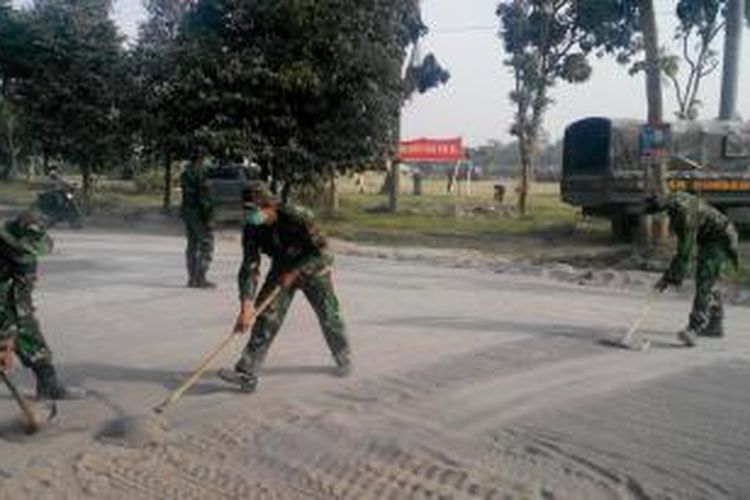 Anggota TNI membersihkan jalan yang tertutup abu vulkanik letusan Gunung Kelud di Kediri, Sabtu (15/2/2014).