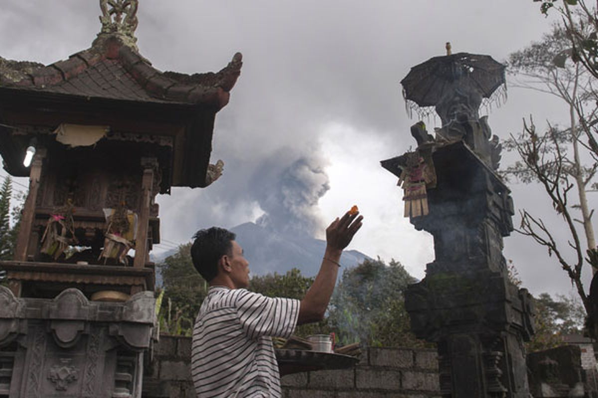 Warga berdoa di rumahnya di Desa Besakih, Karangasem, Bali, Selasa (28/11/2017). Pusat Vulkanologi dan Mitigasi Bencana Geologi memantau kolom abu gunung bertambah tinggi hingga 4.000 meter dalam enam jam terakhir sejak pukul 06.00 Wita pada Selasa (28/11/2017).