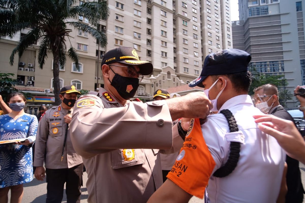 Polisi memakaikan bet pengawas protokol kesehatan COVID-19 pada petugas security sebagai pelantikan simbolik, pada kegiatan penetapan Apartemen Bebas COVID-19 di Apartemen Mediterania 2, Jakarta Barat (1/10/2020).