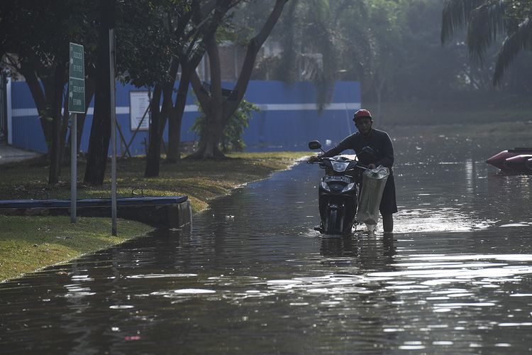 Pengendara mendorong motornya yang mogok saat melintasi banjir rob di Kompleks Pantai Mutiara, Penjaringan, Jakarta, Minggu (7/6/2020). Banjir di kawasan tersebut diduga akibat adanya tanggul yang jebol saat naiknya permukaan air laut di pesisir utara Jakarta.