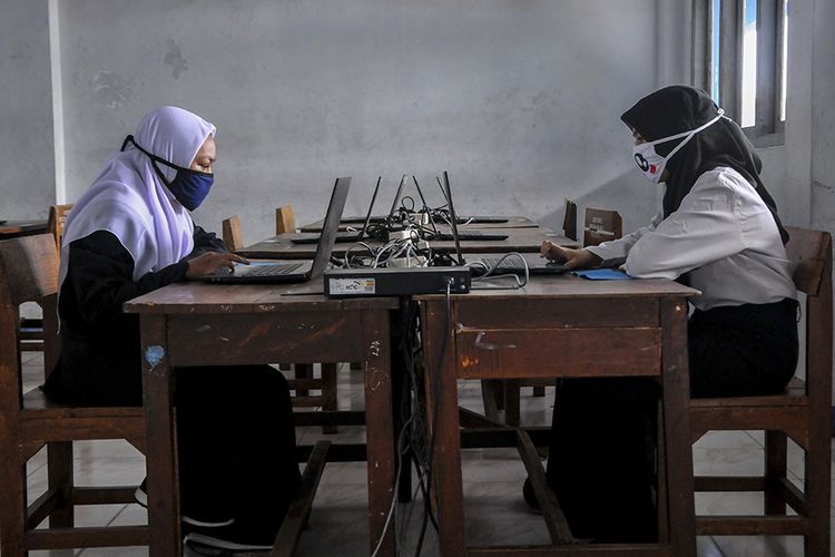 Dua siswi sekolah mengikuti Penilaian Akhir Semester (PAS) di Sekolah Menengah Kejuruan Bina Karya Mandiri 2, Bekasi, Jawa Barat, Senin (8/6/2020). Menurut pihak sekolah, siswa yang mengikuti ujian di sekolah mempunyai kendala secara teknis untuk mengikuti ujian secara daring di rumahnya masing-masing.