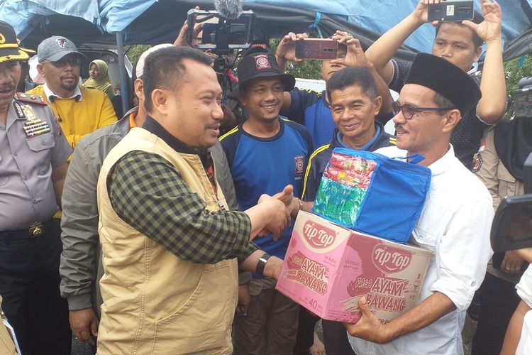 Bupati Kampar, Catur Sugeng Susanto (kiri) menyerahkan bantuan sembako untuk para korban banjir di Kecamatan Gunung Sahilan, Kabupaten Kampar, Riau, Rabu (11/12/2019).