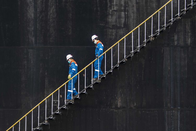Pekerja PT Pertamina Hulu Rokan menaiki anak tangga tangki pengumpul produksi minyak (Tank Farm) di Blok Rokan, Dumai, Riau.