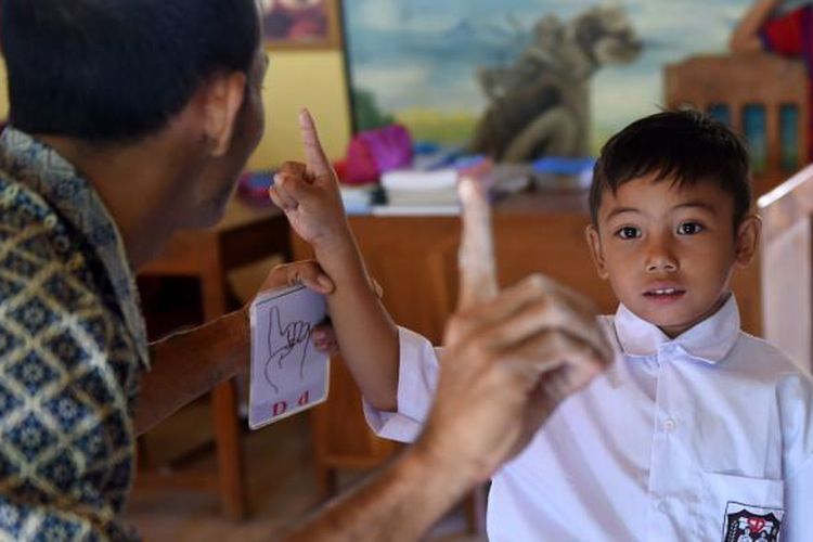 Guru mengajar menggunakan bahasa isyarat kepada seorang murid tunarungu di Sekolah Dasar, di Desa Bengkala, Singaraja, Bali, 20 Juli 2016. Desa Bengkala telah menjadi rumah bagi sejumlah besar penyandang tunarungu turun temurun.