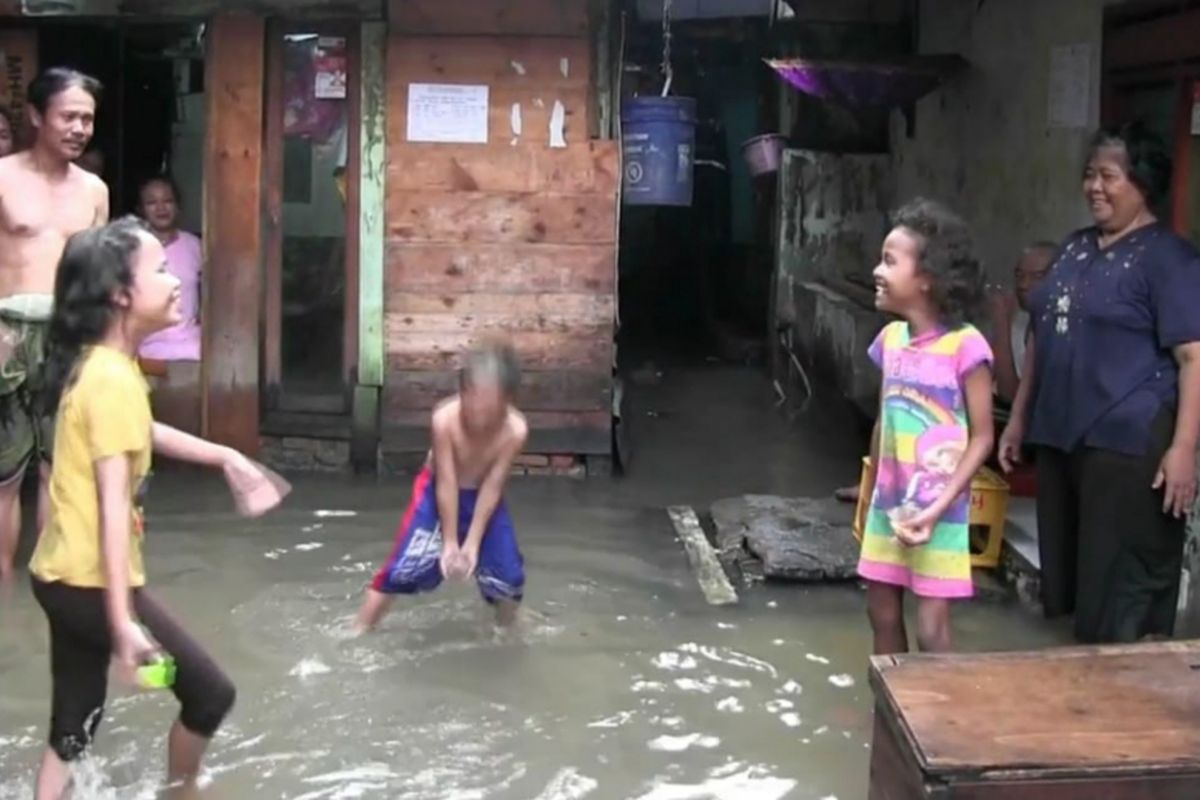 Anak kecil asyik menikmati banjir yang merendam pemukiman mereka di RT 016 RW 005 Rawa Terate, Cakung, Jakarta Timur, Rabu (30/1/2019)
