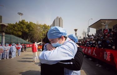 Seorang pekerja medis (R) merangkul anggota tim bantuan medis dari provinsi Jiangsu pada upacara yang menandai keberangkatan mereka setelah membantu upaya pemulihan virus corona COVID-19, di Wuhan, di provinsi Hubei tengah Cina pada 19 Maret 2020.