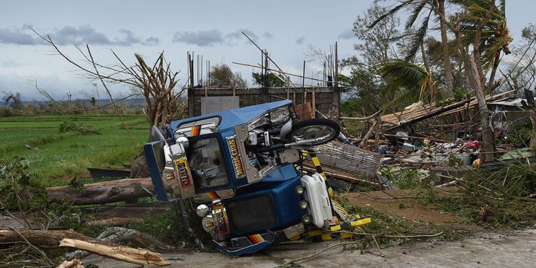 Sebuah kendaraan roda tiga yang terbalik terlihat di samping rumah yang hancur setelah Topan Mangkhut mengantam Kota Alcala, provinsi Cagayan, Sabtu (15/9/2018). Topan Mangkhut terus bergerak menerjang China selatan setelah sebelumnya menewaskan sedikitnya 64 orang di Filipina dan menyebabkan kerusakan parah di Hongkong.