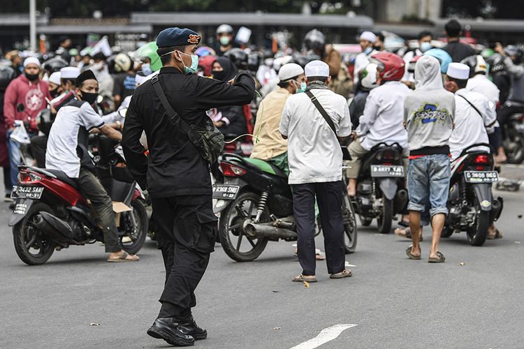 Seorang personel Brimob Polri berusaha menghalau massa aksi demonstrasi 1812,  di kawasan Medan Merdeka Selatan, Jakarta, Jumat (18/12/2020). Kepolisian membubarkan paksa massa aksi demonstrasi dikarenakan angka penyebaran Covid-19 masih tinggi di wilayah Jakarta.