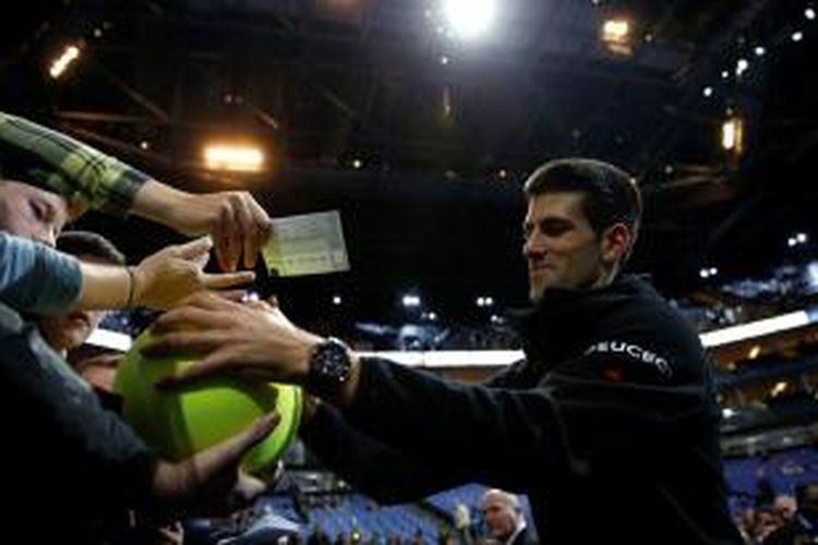 Petenis Serbia, Novak Djokovic, memberikan tanda tangan kepada penonton setelah memenangi laga melawan petenis Kroasia, Marin Cilic, pada laga pertama Gru[ A ATP World Tour Finals di London, Senin (10/11/2014). Djokovic menang 6-1, 6-1.