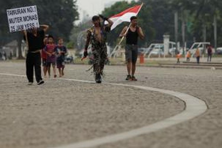 Kopral Bagyo (dua kiri) memikul batu saat berjalan memutari Tugu Monumen Nasional di Jakarta, Sabtu (06/07/2013). Kopral Bagyo berencana untuk memutari monas selama 25 jam dalam rangka hari ulang tahun Polisi Militer dan kampanye hidup sehat tanpa narkoba. 