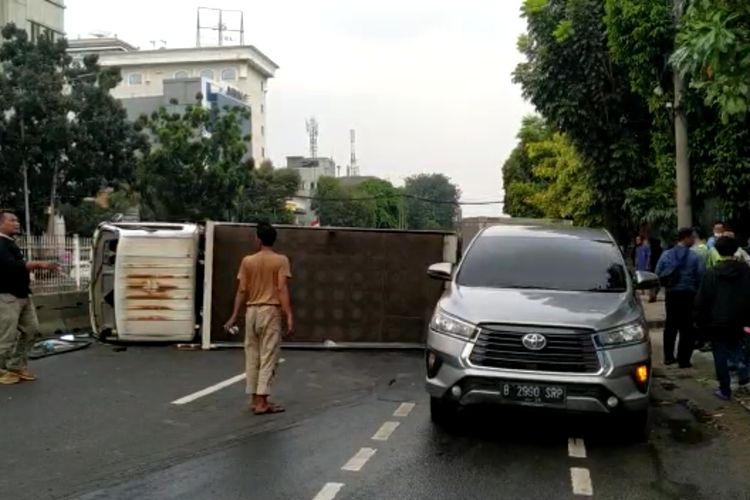 Penampakan truk pengangkut galon air mineral terguling di bilangan Mampang Prapatan, Jakarta Selatan, Selasa (2/5/2023). 