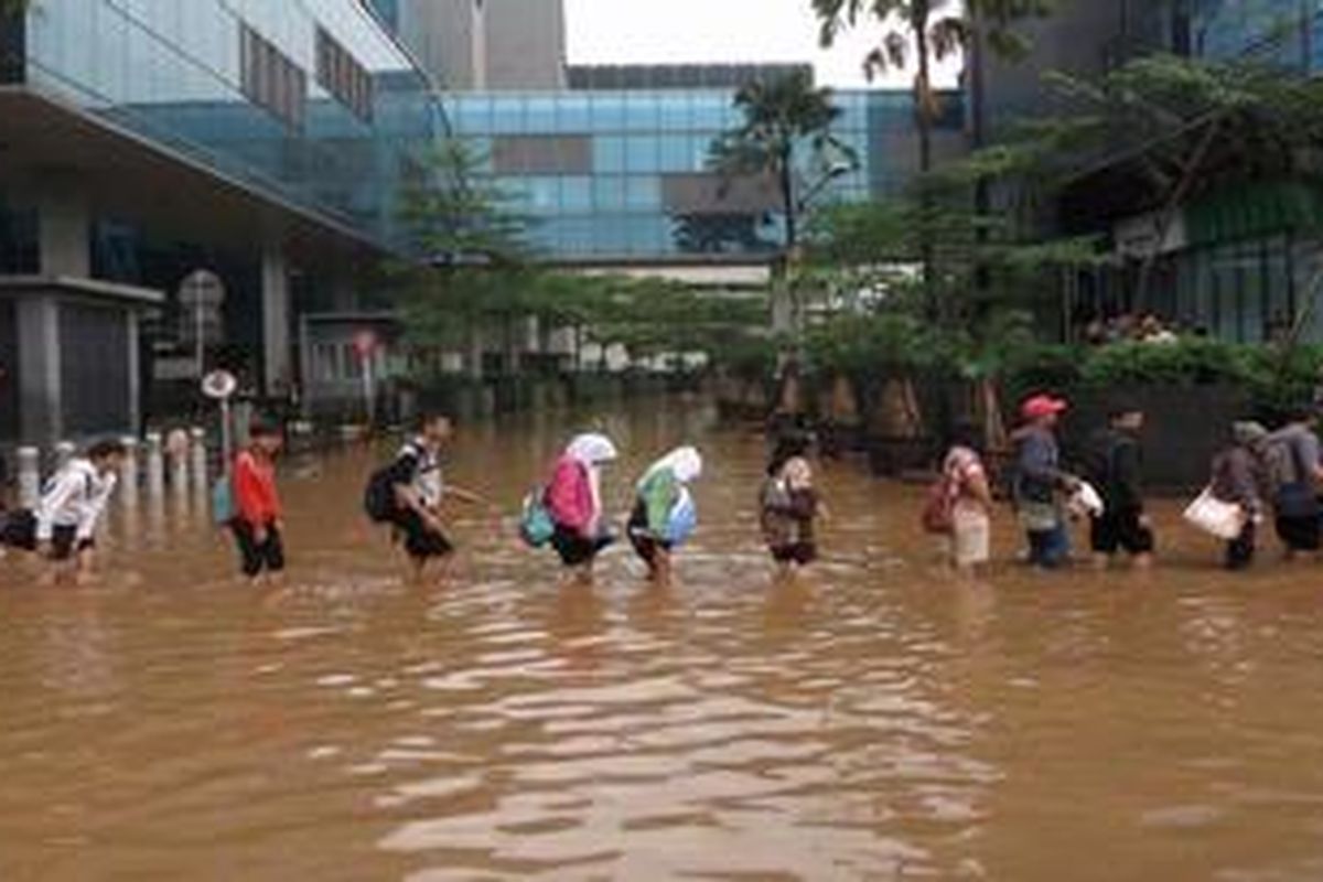 Karyawan yang akan menuju tempat kerja terpaksa beriringan menerobos banjir yang masih menggenangi Jalan MH Thamrin di sekitar Bundaran Hotel Indonesia, Jakarta, Jumat (18/1/2013) pagi. Banjir yang menggenangi sebagian wilayah Jakarta membuat arus lalu lintas dan perekonomian terganggu.