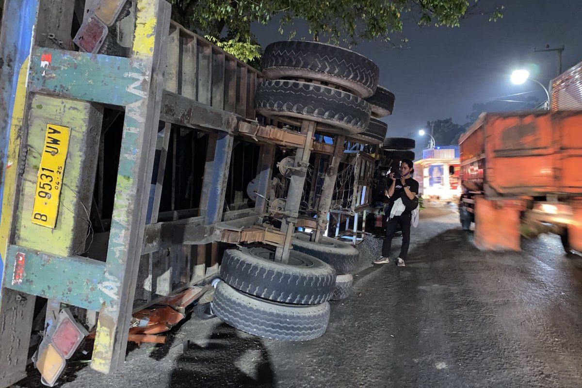 Satu unit truk kontainer bernomor polisi B 9531 UMV yang terguling di Jalan Raya Narogong, Bantargebang, Kota Bekasi, Rabu (17/5/2023). Akibat kecelakaan itu, satu unit angkutan kota (angkot) yang sedang ngetem ringsek akibat tertimpa peti kemas.