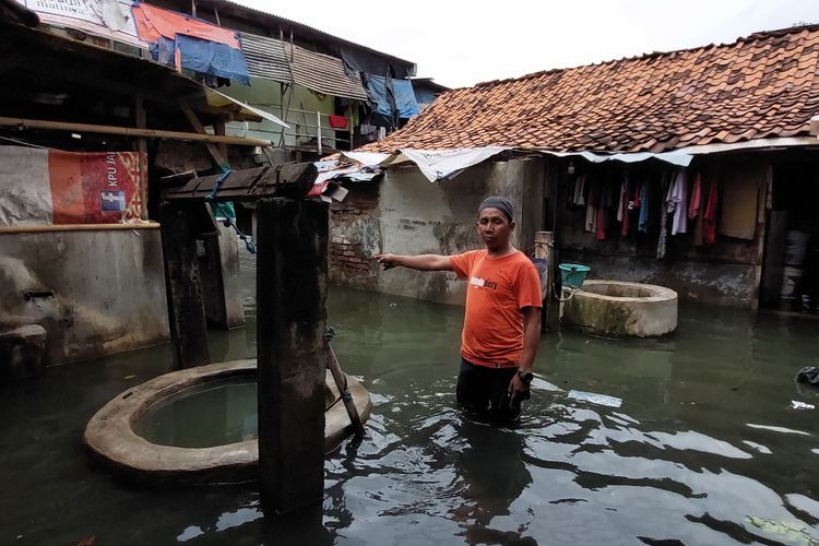 Junaidi warga RT 15 RW 03 berjalan dengan banjir setinggi lutut di sekitar kediamannya di sekitar Kali Semongol, Tegal Alur, Jakarta Barat, Kamis (20/1/2022)  pukul  15.07 WIB.