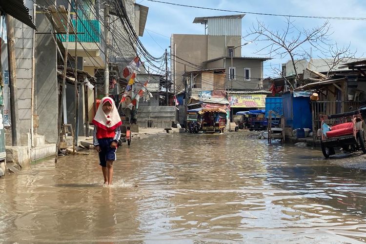 Banjir melanda ruas jalan di Muara Angke, Penjaringan, Jakarta Utara pada Rabu (21/12/2022) siang. Para warga pun harus berjalan secara hati-hati untuk melewati genangan. 