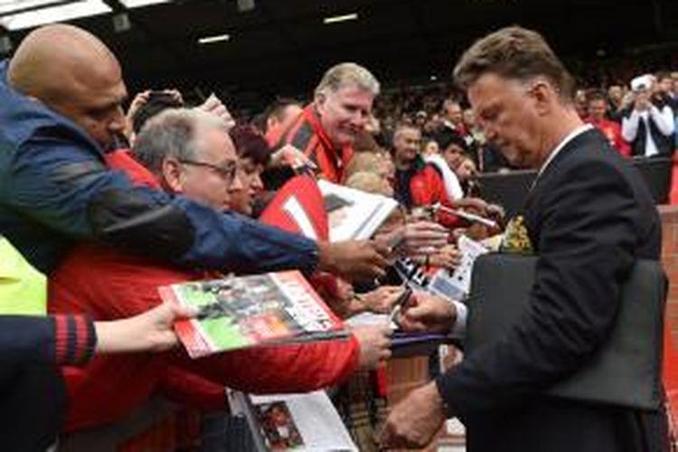 Manajer Manchester United, Louis van Gaal (kanan), melayani permintaan tanda tangan sejumlah suporter, sebelum pertandingan Premier League, antara timnya dan Swansea City, di Old Trafford, 16 Agustus 2014.