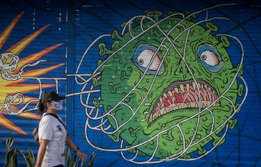 Warga melintas di depan mural bertema COVID-19 di Kemplayan, Solo, Jawa Tengah, Minggu (21/2/2021). Berdasarkan hasil evaluasi Pemerintah, Pemberlakukan Pembatasan Kegiatan Masyarakat (PPKM) mikro pada periode pertama mampu menurunkan jumlah kasus aktif COVID-19 sekitar 17,27 persen dalam sepekan, untuk itu Pemerintah kembali memperpanjang PPKM mikro selama dua pekan yaitu mulai 23 Februari hingga 8 Maret 2021. ANTARA FOTO/Mohammad Ayudha/foc.