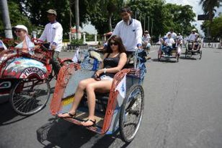 Wisatawan asing asal Belgia menaiki becak untuk menikmati suasana kota di kawasan Titik Nol, Yogyakarta, Selasa (2/4/2013). Berwisata dengan becak merupakan salah satu paket wisata yang banyak diminati wisatawan asing saat berkunjung di Yogyakarta. 