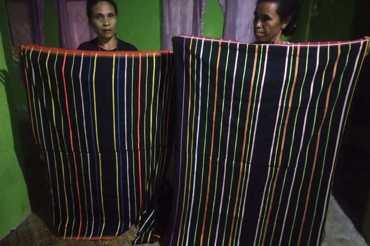 Dari kiri ke kanan- Mama Petronela Evi (46) dan Mama Regina Inus (56) sedang memegang hasil tenun Puncatiti di Kampung Wangkar, Desa Ranamese, Kecamatan Congkar, Kab. Manggarai Timur, NTT, Sabtu, (11/3/2023). (KOMPAS.com/MARKUS MAKUR)