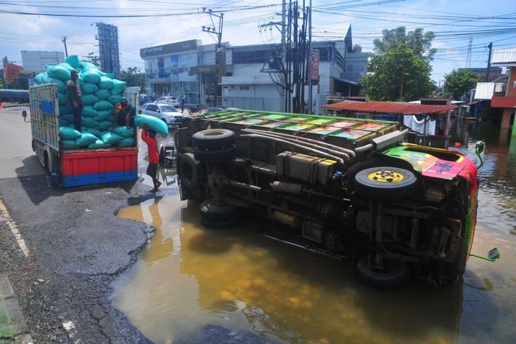 Pekerja mengangkat gabah dari mobil truk yang mengalami kecelakaan di jalan jalur Pantura, Jati Wetan, Kudus, Jawa Tengah, Senin (6/3/2023).