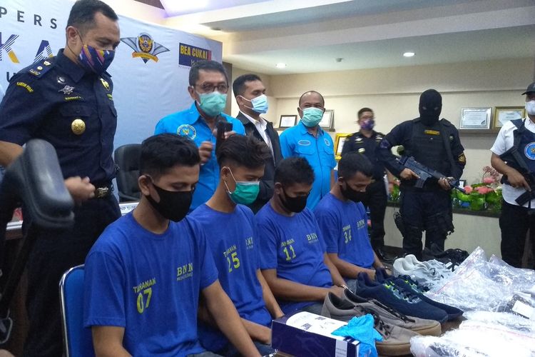 Empat orang tersangka menunjukkan sepatu yang digunakannya untuk menyembunyikan 2 kg sabu saat akan terbang ke Solo. Mereka ditangkap di Bandara Internasional Kualanamu pada Jumat (22/1/2021) sore.