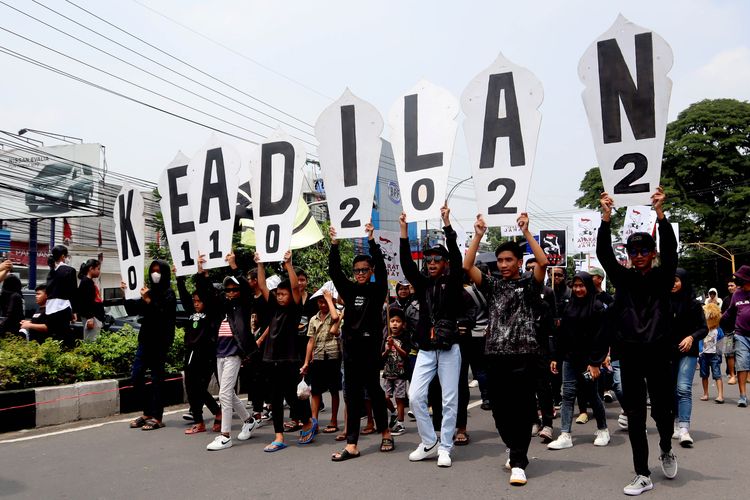 Suporter Arema, Aremania dan masyarakat melakukan aksi damai dengan mengakat tulisan tuntutan KEADILAN terkait Tragedi Kanjuruhan yang dilaksanakan di sejumlah titik Kota Malang, Minggu (04/12/2022) siang.