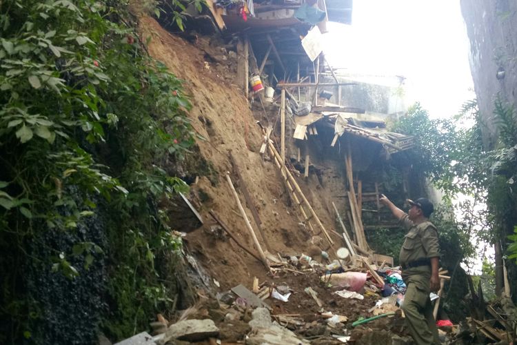Petugas Satpol PP kecamatan Cidadap tengah menunjukan lokasi rumah yang roboh lantaran lereng yang longsor dibawahnya. satu orang meninggal dunia tertimbun longsoran.