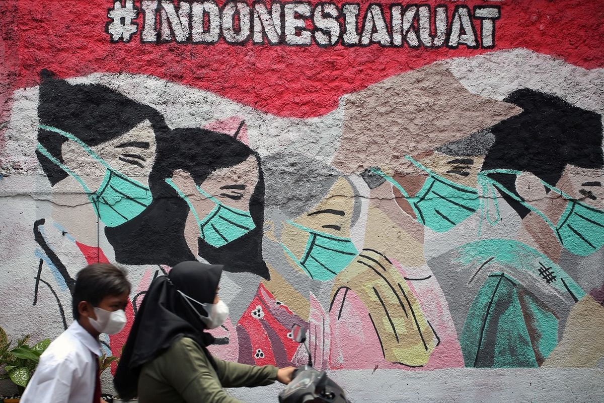 Pengendara motor melintas di depan mural yang bergambar ajakan menggunakan masker yang ada di kawasan Cireunde, Tangerang Selatan, Banten, Selasa (15/2/2022). Tingginya angka penyebaran dan penularan COVID-19 di Tangsel membuat sejumlah warga mengajak warga yang lain tetap patuh terus menggunakan masker di tengah mulai memudarnya ketaatan penggunaan masker demi meminimalisir penyebaran COVID-19. ANTARA FOTO/Muhammad Iqbal/foc.