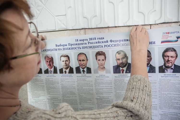 Anggota Komisi Pemilihan lokal memasang poster kandidat presiden jelang pelaksanaan Pemilu di Krimea, Sabtu (17/3/2018).