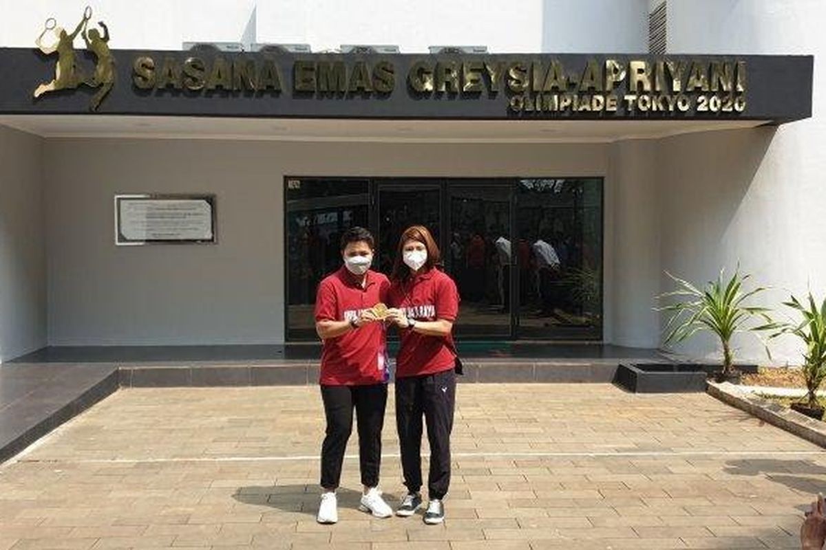 Pebulutangkis peraih emas pada Olimpiade Tokyo 2022, Greysia Polii (kanan) dan kompatriotnya di nomor ganda putri, Apriyani Rahayu (kiri), berpose di depan Sasana Emas Greysia-Apriyani di GOR Ragunan, Jakarta Timur.