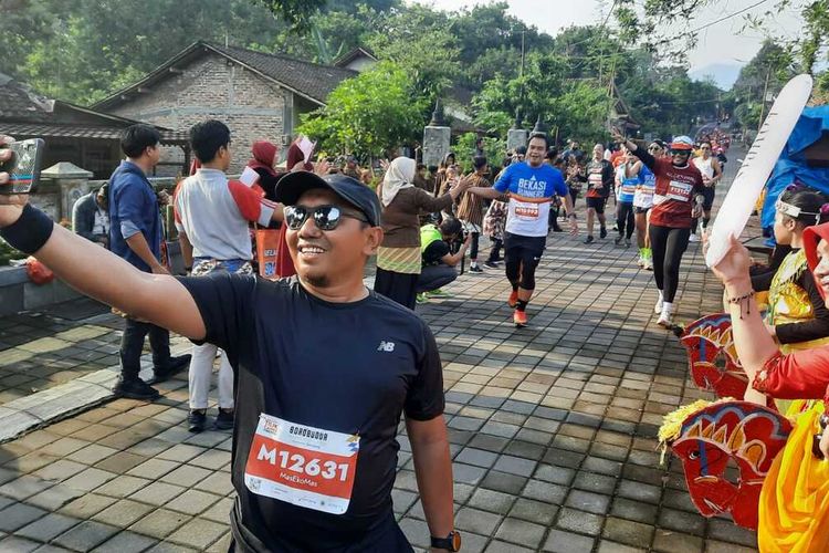 Pelari Borobudur Marathon 2022 menyempatkan diri berfoto dengan warga yang menyambutnya, di Desa Wanurejo, Kecamatan Borobudur, Kabupaten Magelang, Minggu (13/11/2022),