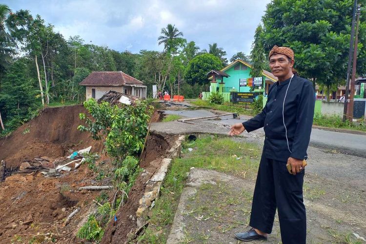 Kepala Desa Girikencana Kecamatan Parungponteng Kabupaten Tasikmalaya, Jawa Barat, Robai menunjukkan longsoran jalan dan SDN 2 Parungponteng yang rawan amblas jika terjadi longsor susulan pada Rabu (2/11/2022).