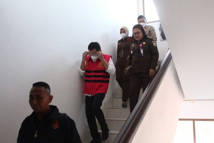 Tersangka memakai rompi merah muda saat menuruni tangga didampingi tim penuntut umum Kejati Sulut, Kamis (9/6/2022). Tersangka RRJL alias Icad (49) kemudian digiring ke Rutan Polda Sulut.