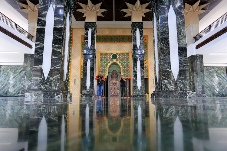 Sejumlah pengunjung melihat suasana di dalam Masjid Giok atau Masjid Agung Baitul A'la Desa Lueng Baro, Suka Makmur, Nagan Raya, Aceh, Minggu (10/4/2022). Masjid Agung Baitul A'la Nagan Raya yang dibangun sejak tahun 2012 tersebut dirancang menggunakan perpaduan arsitektur khas Asia Tenggara, Timur Tengah dan Aceh dengan ornamen berlapis batu giok pada lantai, dinding, tiang dan kubah masjid yang proses pembangunannya memasuki tahap penyelesaian atau sekitar 80 persen sehingga akan dibuka untuk umum pada Juni 2022 mendatang. ANTARA FOTO/Syifa Yulinnas/nym.