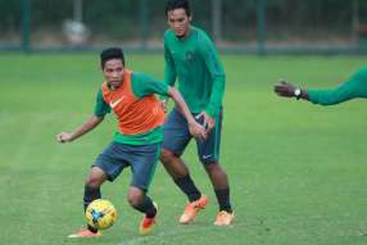 Evan Dimas (rompi oranye) menggiring bola pada sesi latihan tim nasional Indonesia di Lapangan Sekolah Pelita Harapan, 1 November 2016.
