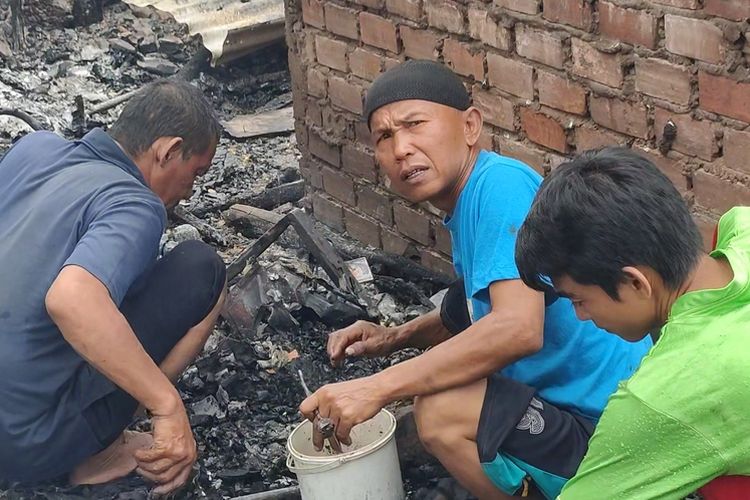 Anes (kaos biru) dibantu keluarganya membongkar puing sisa kebakaran mencari uang koin yang ia simpan dalam celengan yang turut hangus terbakar dalam peristiwa kebakaran Rabu pagi di Desa Ibul Besar 3 Kecamatan Pemulutan Ogan Ilir

2. Uang koin pecahan seribuan yang berhasil ia kumpulkan ia masukkan ke dalam ember yang kondisinya sudah hitam hangus terbakar.