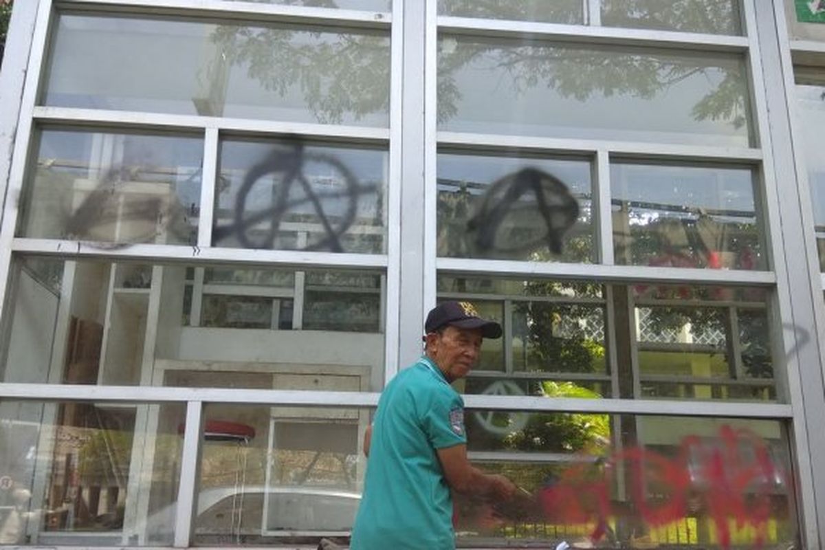 Seorang pekerja sedang membersihkan coretan di halte Jalan Surapati,  Kota Bandung, Jawa Barat.
