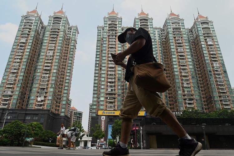 Seorang warga berjalan di depan properti milik Evergrande di Guangzhou, China. Foto diambil 17 September 2021.
