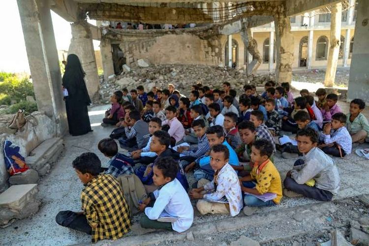 Para siswa menghadiri kelas pada hari pertama tahun ajaran baru di sekolah mereka yang hancur akibat serangan udara 2016