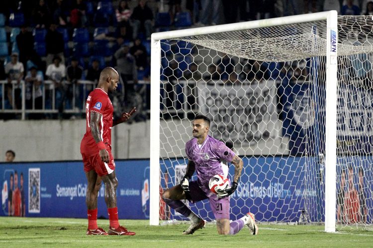 Penjaga gawang Arema FC Lucas Frigeri menggagalkan tendangan pemain Malut United David da Silva saat laga pekan ke-26 Super League 2025-2026 yang berakhir dengan skor 1-1 di Stadion Kanjuruhan Kepanjen, Kabupaten Malang, Jumat (3/4/2026) sore.