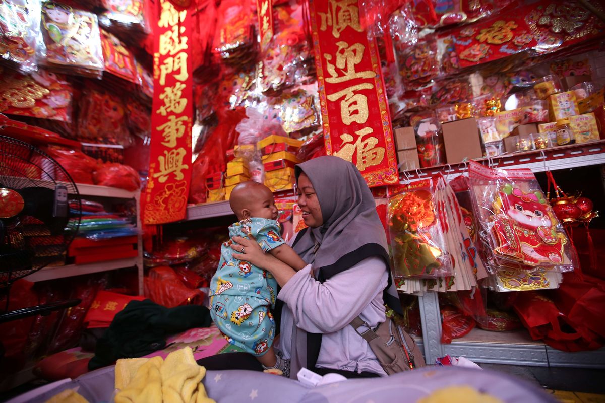 Diantara pernak-pernik dagangannya, seorang penjual bermain bersama anaknya ketika menunggu pembeli datang di Kawasan Glodok Pancoran, Jakarta Barat pada Jumat (19/1/2024).