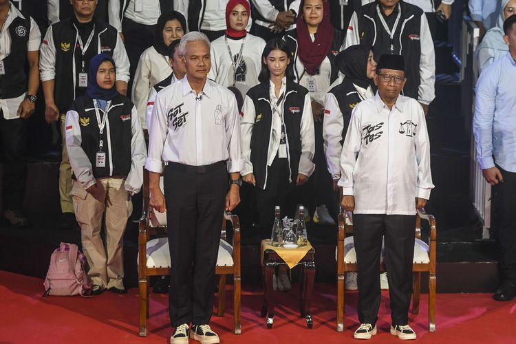 Pasangan Capres-Cawapres nomor urut tiga Ganjar Pranowo (depan kiri) dan Mahfud MD (depan kanan) berdiri sebelum debat perdana Capres dan Cawapres 2024 di Gedung KPU, Jakarta, Selasa (12/12/2023). Berikut serba-serbi busana capres cawapres saat debat.
