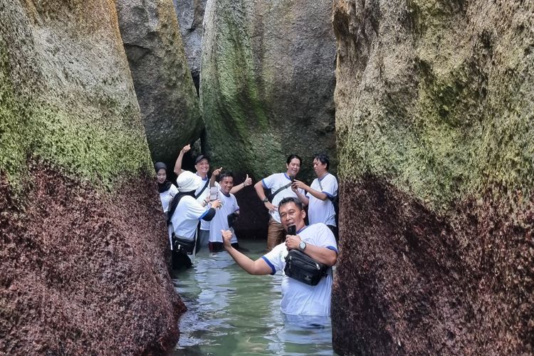 Pengunjung berfoto di celah bebatuan granit Pulau Kelayang, Belitung, Jumat (18/10/2024).