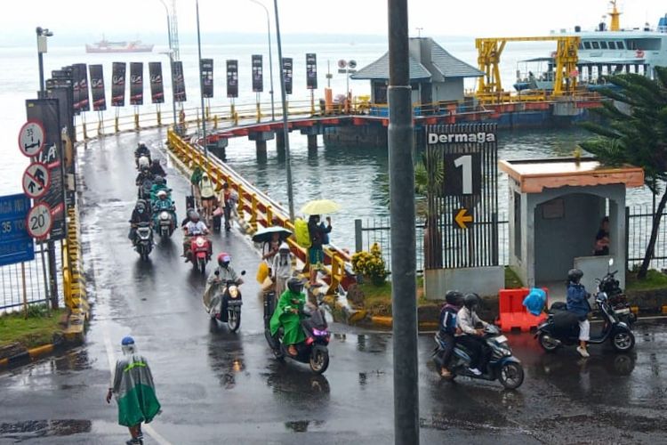 Para penumpang memakai payung saat turun dari kapal di Pelabuhan ASDP Ketapang Banyuwangi karena diguyur hujan deras dan angin kencang, Selasa (9/4/2024).