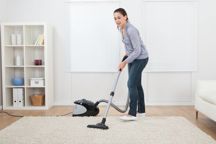 Ilustrasi membersihkan karpet dengan vacuum cleaner. 