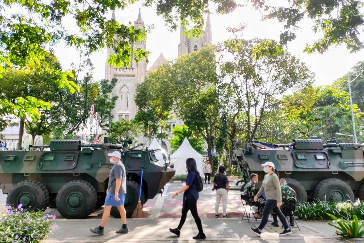 Sejumlah warga berjalan di depan Gereja Katedral, Jakarta Pusat yang dijega ketat personel TNI-Polri, Jumat (2/4/2021).