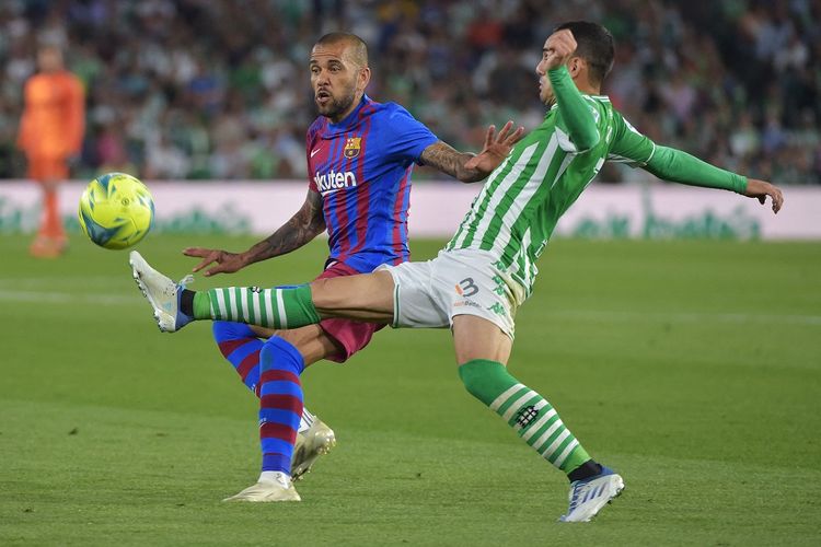 Pemain Barcelona Dani Alves (kiri) berduel dengan penyerang Real Betis Juanmi dalam laga lanjutan Liga Spanyol di Stadion Benito Villamarin pada Minggu (8/5/2022) dini hari WIB.