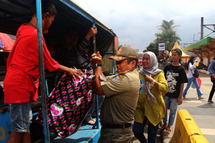 Petugas membantu warga yang hendak naik mobil patroli Satpol PP DKI Jakarta di Jalan Jatibaru, Tanah Abang, Jakarta, Rabu (31/01/2018). Mobil tersebut tidak sengaja beroperasi karena karena operasional bus transjakarta Tanah Abang Explorer dihentikan sementara akibat aksi mogok yang dilakukan supir angkot Tanah Abang.